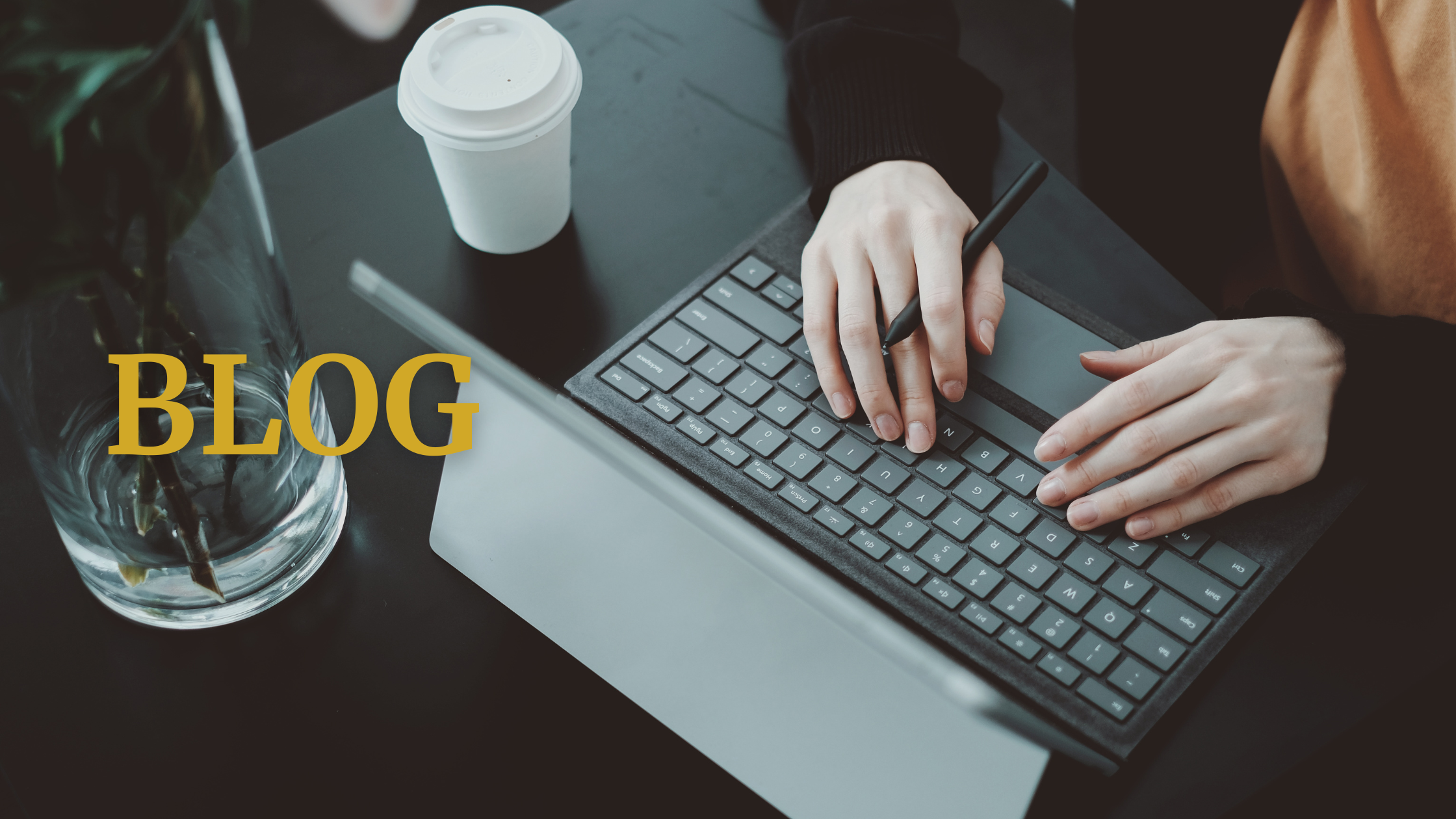 A person typing at a computer with gold writing that says "BLOG" on top